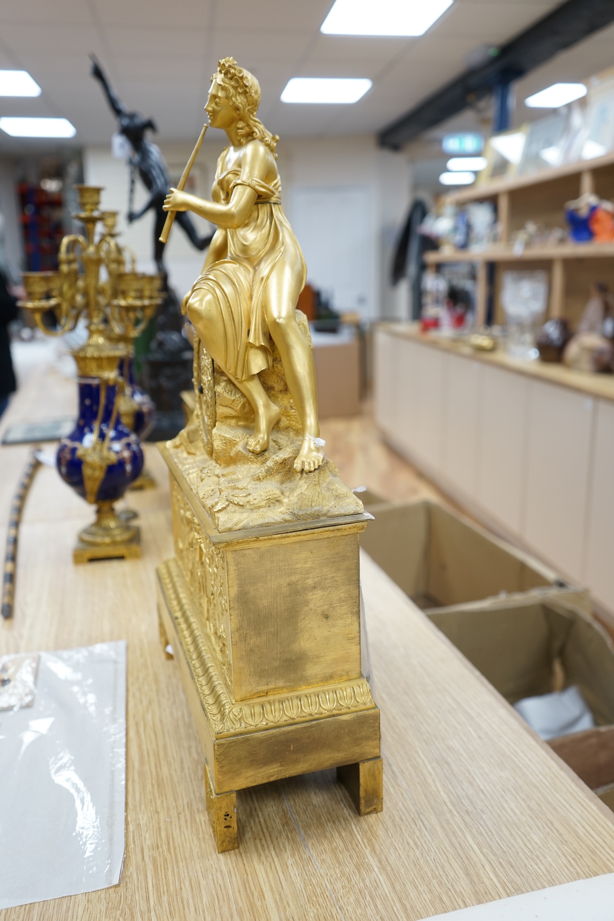 A French Louis Philippe period Empire ormolu clock, with seated classical female upon a rock enclosing the dial, the whole upon a square base with allegorical patch in relief, c.1830, with key, 57cm high. Condition - fai